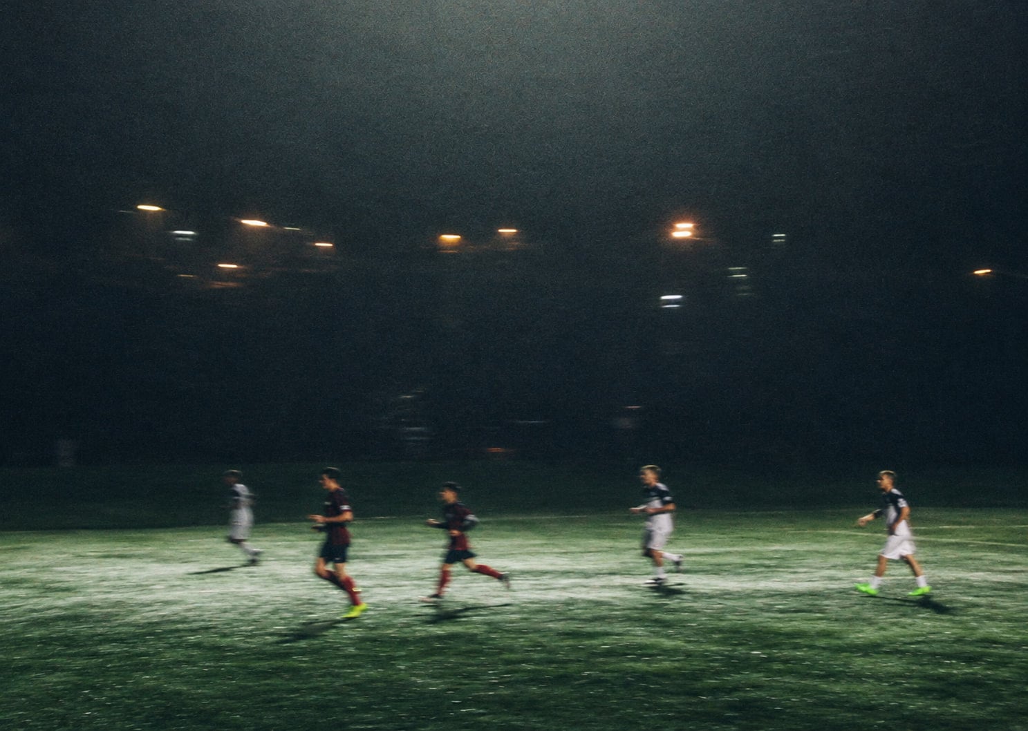 Jogadores disputam uma partida num gramado iluminado à noite